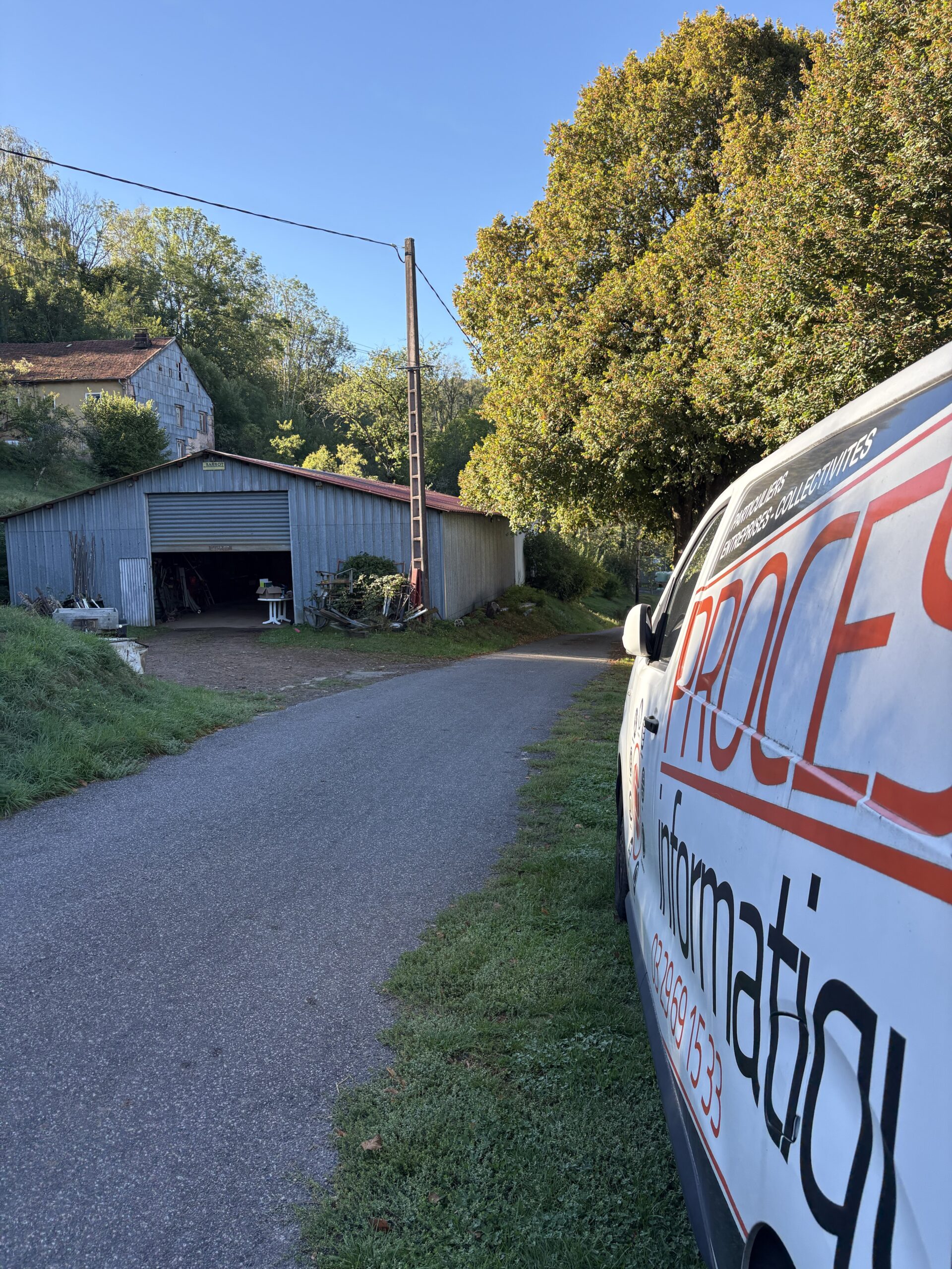 Véhicule Process Informatique garé près d'un bâtiment agricole à Tendon